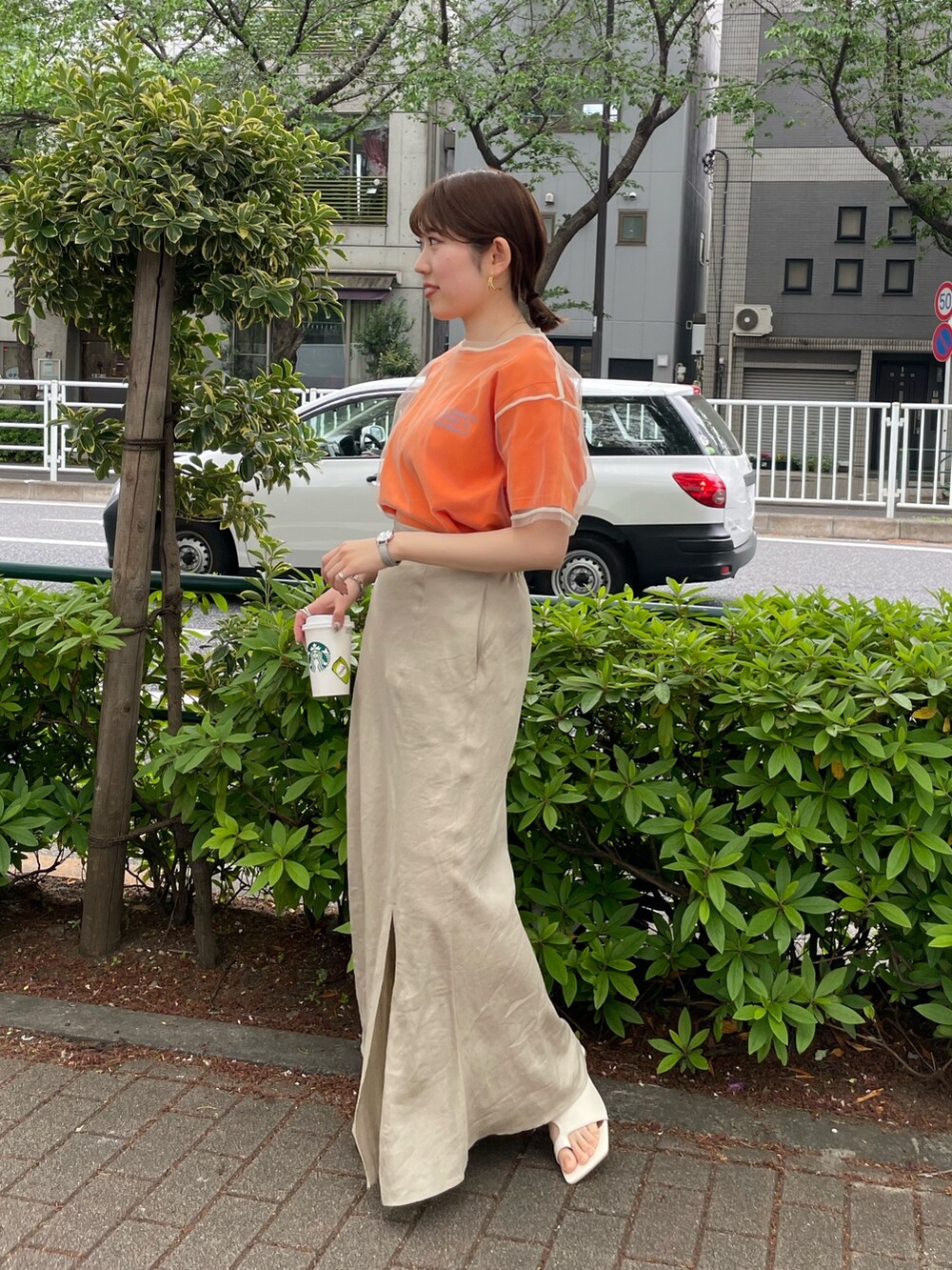 ホワイト系のサンダル、オレンジ系のTシャツ/カットソー、ベージュ系のスカートを着用したレディースの春コーディネートの2枚目の写真