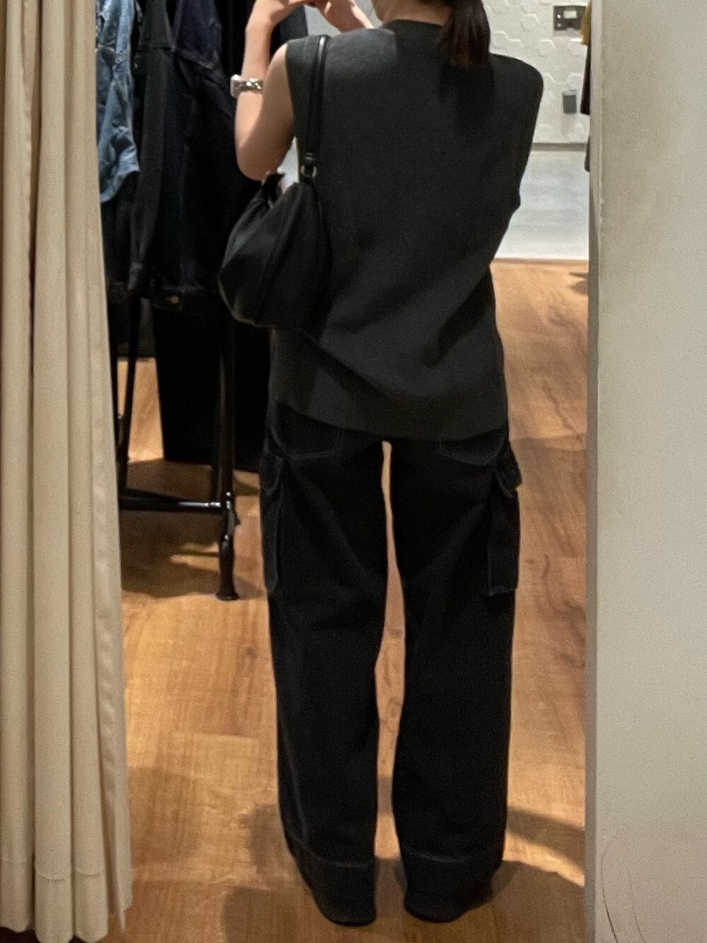 グレー系のベスト、ブラック系のブーツ、ブラック系のデニムパンツを着用したレディースの秋コーディネートの5枚目の写真