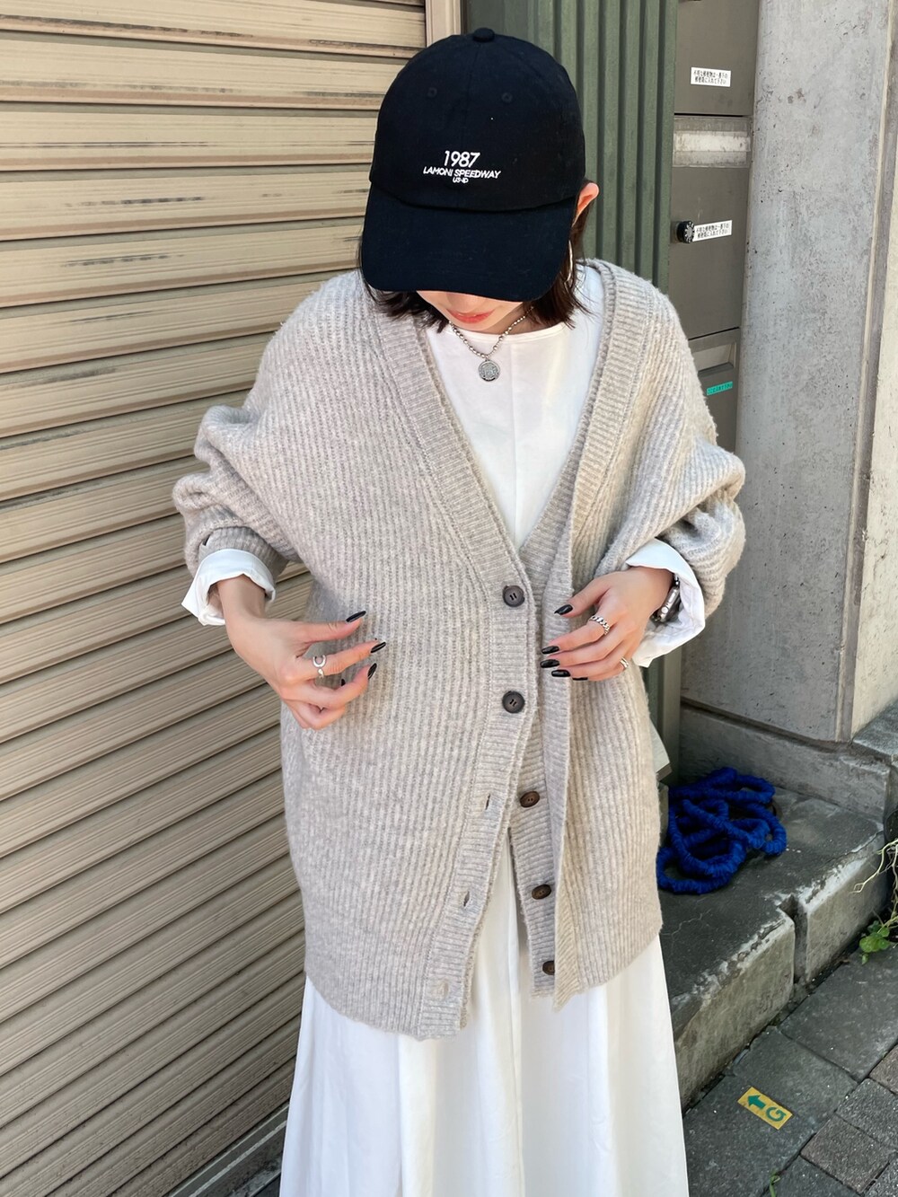 ホワイト系のカーディガン/ボレロ、ブラック系のワンピース、ブラック系のキャップを着用したレディースの秋コーディネートの4枚目の写真