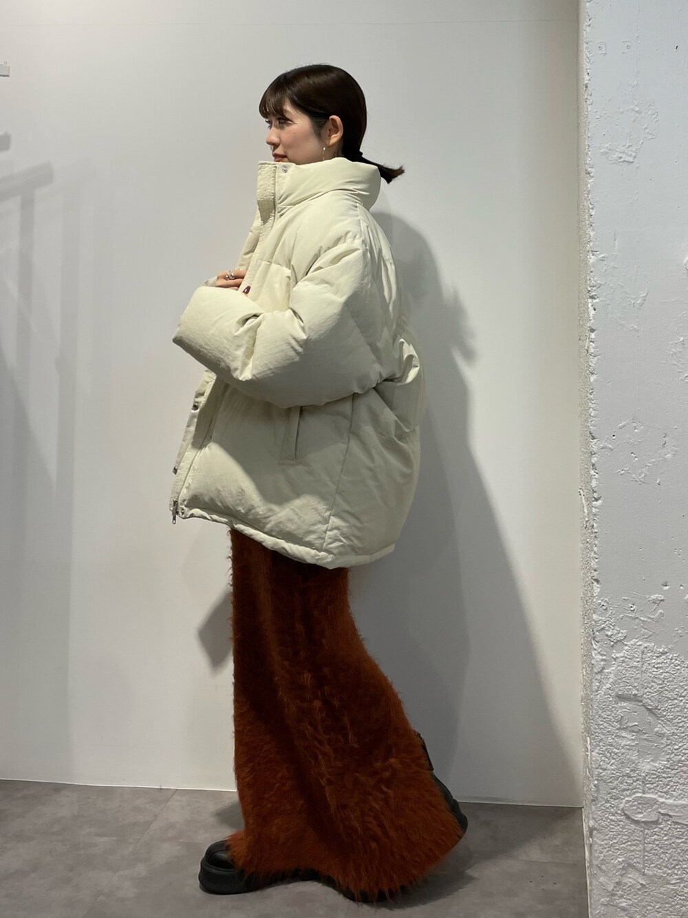 ブラック系のブーツ、ホワイト系のダウンジャケット/コート、オレンジ系のスカートを着用したレディースの秋コーディネートの3枚目の写真