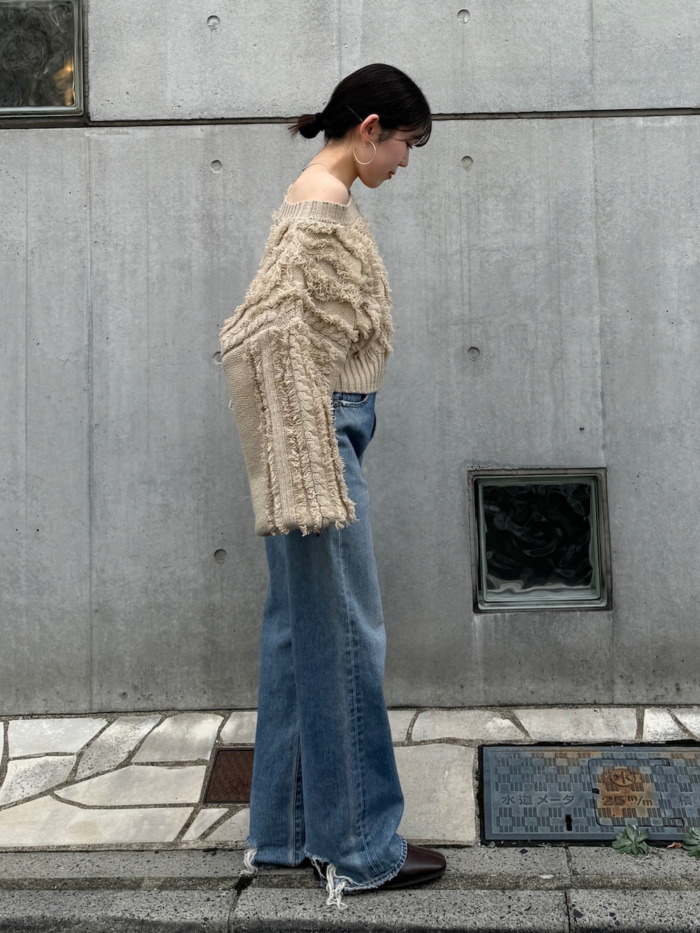 ブルー系のデニムパンツ、グリーン系のトートバッグ、ブラウン系のブーツを着用したレディースの秋コーディネートの2枚目の写真