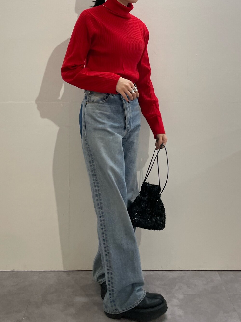 ブルー系のデニムパンツ、ブラック系のハンドバッグ、ブラック系のブーツを着用したレディースの冬コーディネートの3枚目の写真