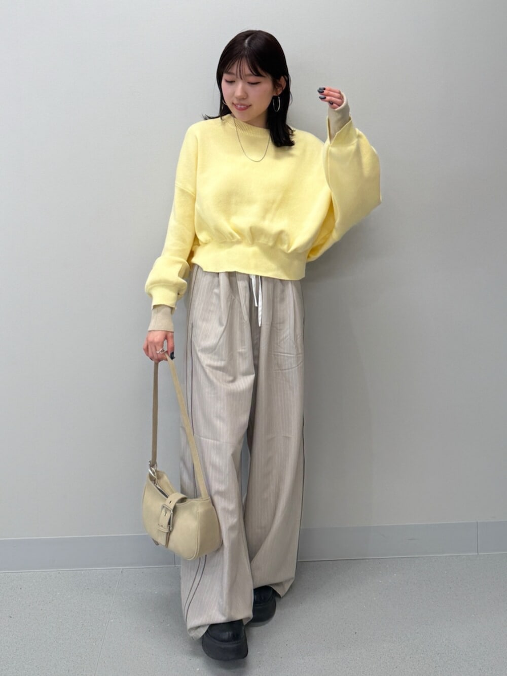 ベージュ系のハンドバッグ、イエロー系のニット/セーター、ブラック系のブーツを着用したレディースの冬コーディネートの2枚目の写真