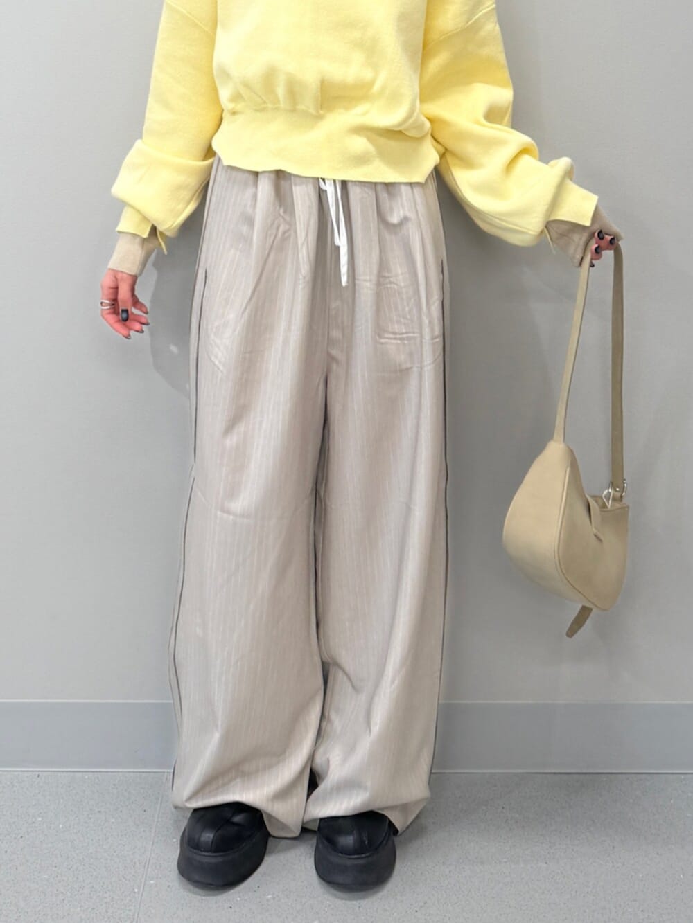 ベージュ系のハンドバッグ、イエロー系のニット/セーター、ブラック系のブーツを着用したレディースの冬コーディネートの6枚目の写真