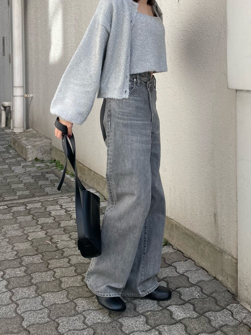 ブラック系のショルダーバッグ、ブラック系のブーツ、ブラック系のデニムパンツを着用したレディースの冬コーディネートの5枚目の写真