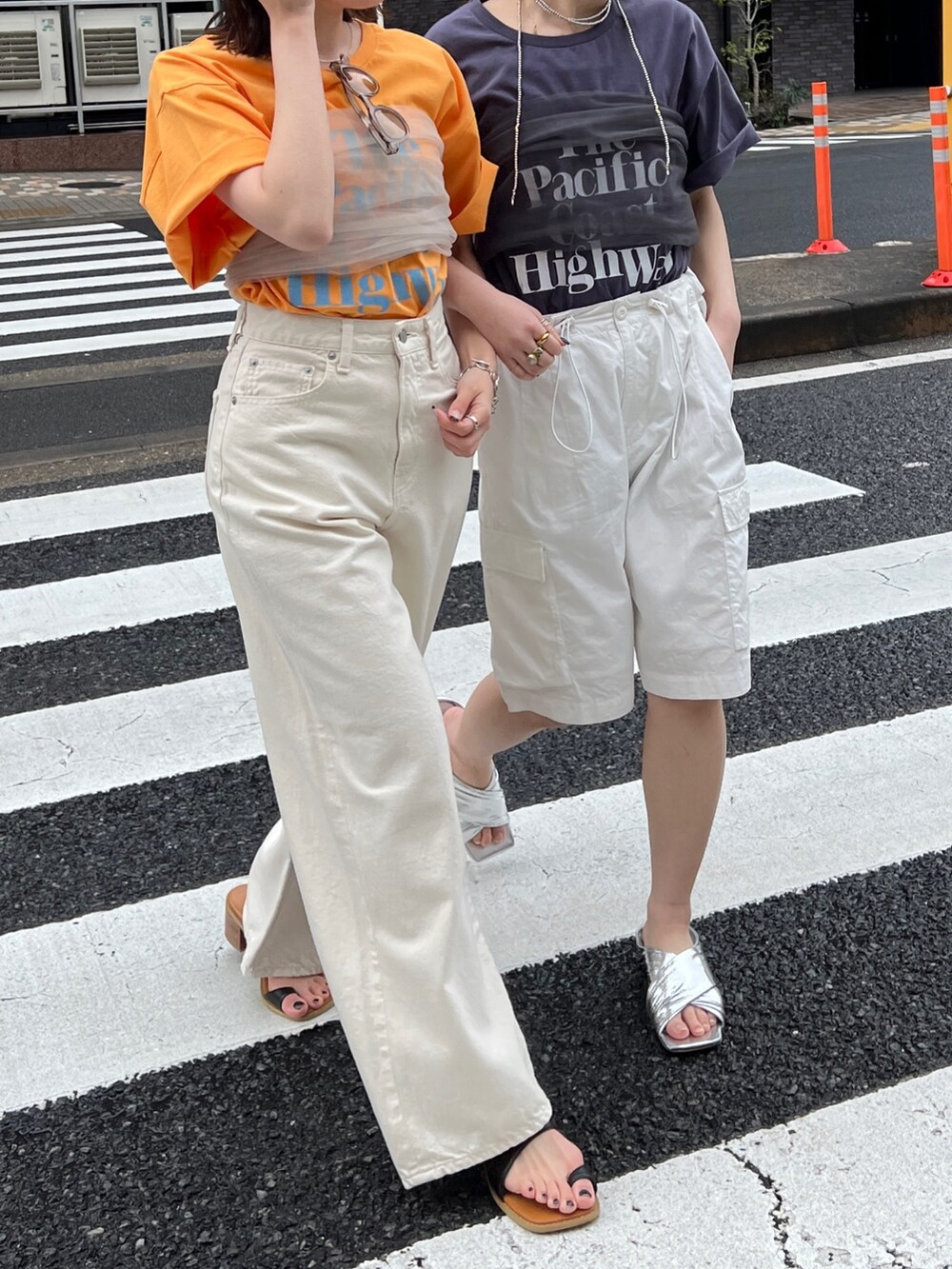 ホワイト系のデニムパンツ、ブラック系のサンダル、オレンジ系のTシャツ/カットソーを着用したレディースの春コーディネートの6枚目の写真