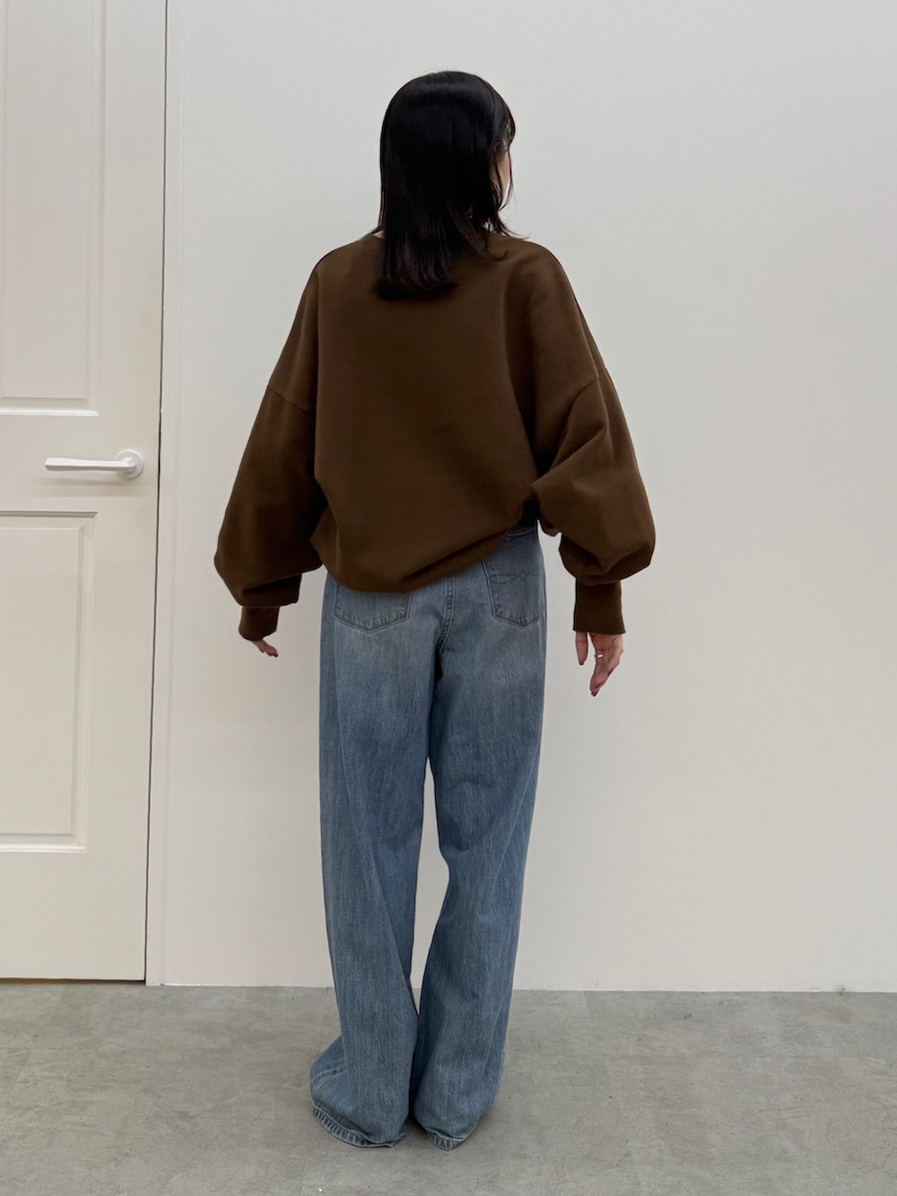 ブルー系のデニムパンツ、ブラック系のブーツ、ブラウン系のスウェットを着用したレディースの秋コーディネートの4枚目の写真