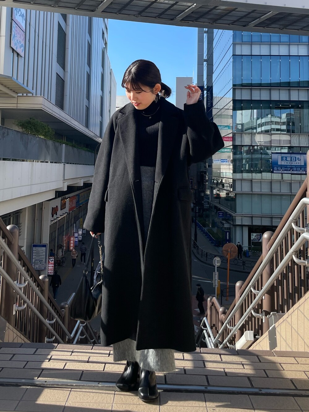 ブラック系のブーツ、ブラック系のチェスターコート、ブラック系のニット/セーターを着用したレディースの冬コーディネートの2枚目の写真