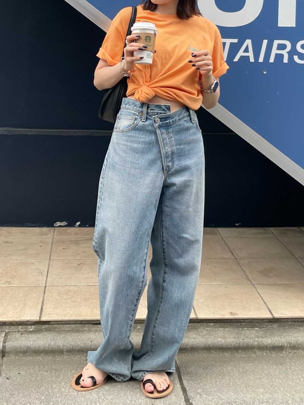 ブラック系のサンダル、ブルー系のデニムパンツ、オレンジ系のTシャツ/カットソーを着用したレディースの夏コーディネートの2枚目の写真
