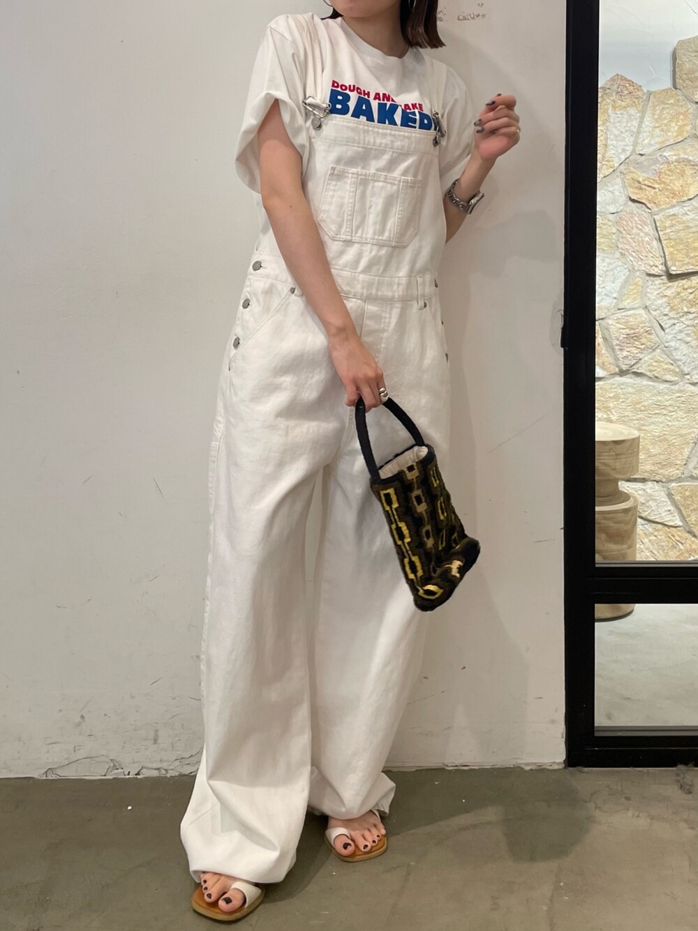 ホワイト系のサンダル、ホワイト系のTシャツ/カットソー、ブラウン系のハンドバッグを着用したレディースの春コーディネートの2枚目の写真