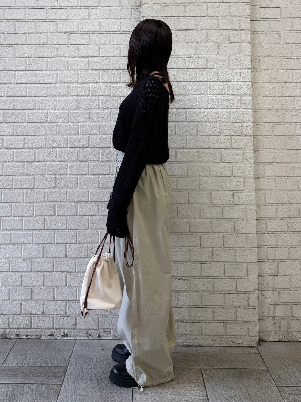 ベージュ系のその他パンツ、ホワイト系のショルダーバッグ、ブラック系のニット/セーターを着用したレディースの春コーディネートの2枚目の写真