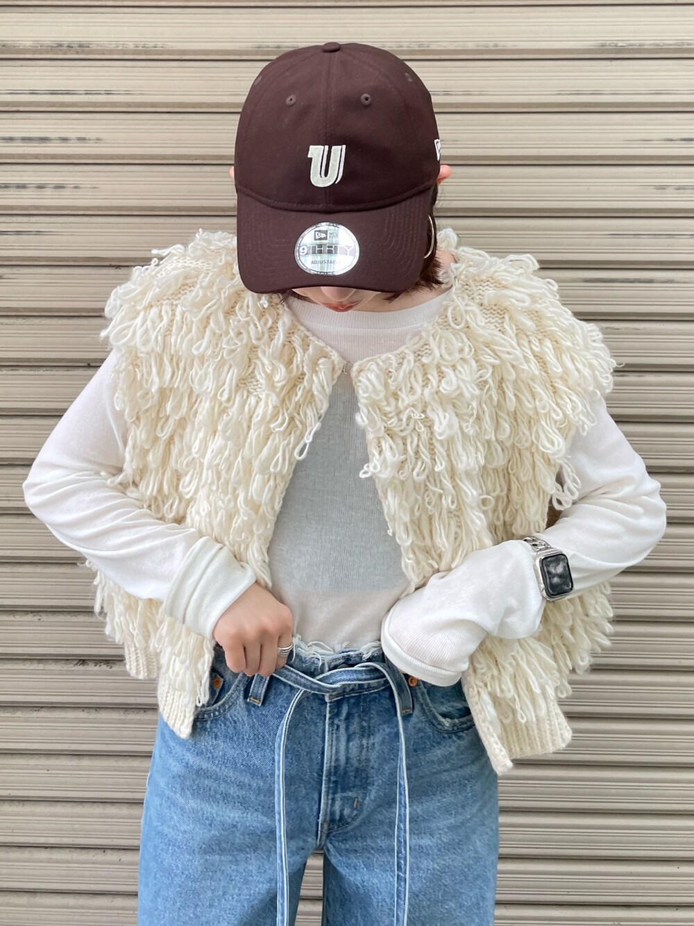 ホワイト系のサンダル、ブルー系のデニムパンツ、ホワイト系のベストを着用したレディースの夏コーディネートの7枚目の写真