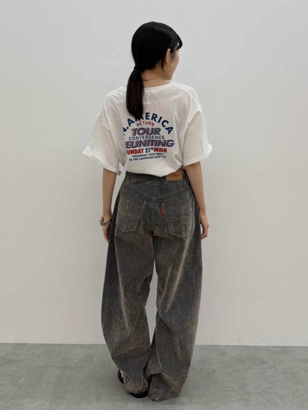 ブラック系のサンダル、ホワイト系のTシャツ/カットソー、ベージュ系のデニムパンツを着用したレディースの夏コーディネートの3枚目の写真