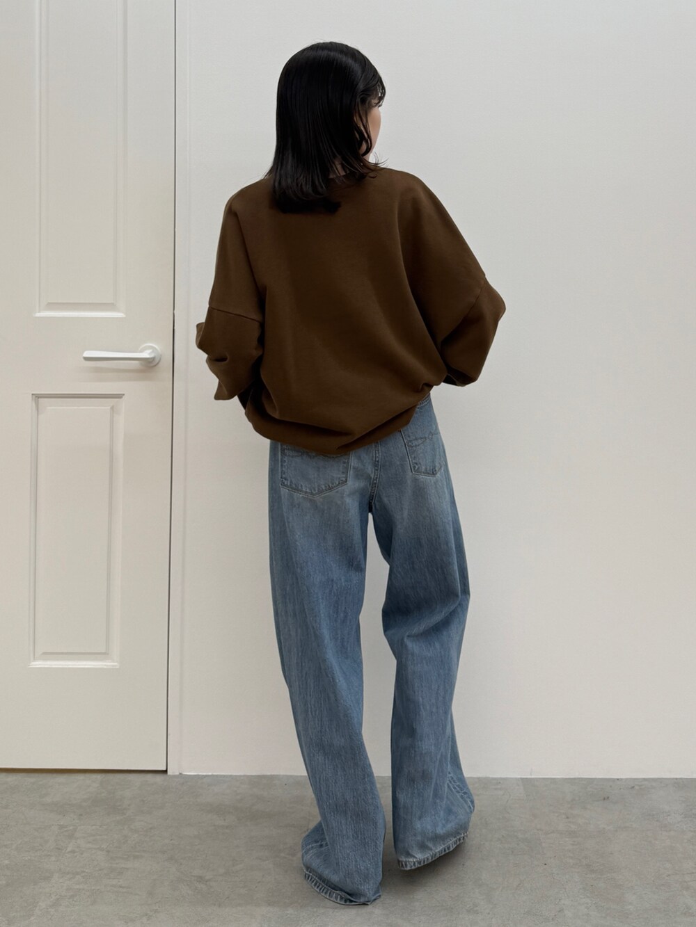 ブルー系のデニムパンツ、ブラック系のブーツ、ブラウン系のスウェットを着用したレディースの秋コーディネートの6枚目の写真