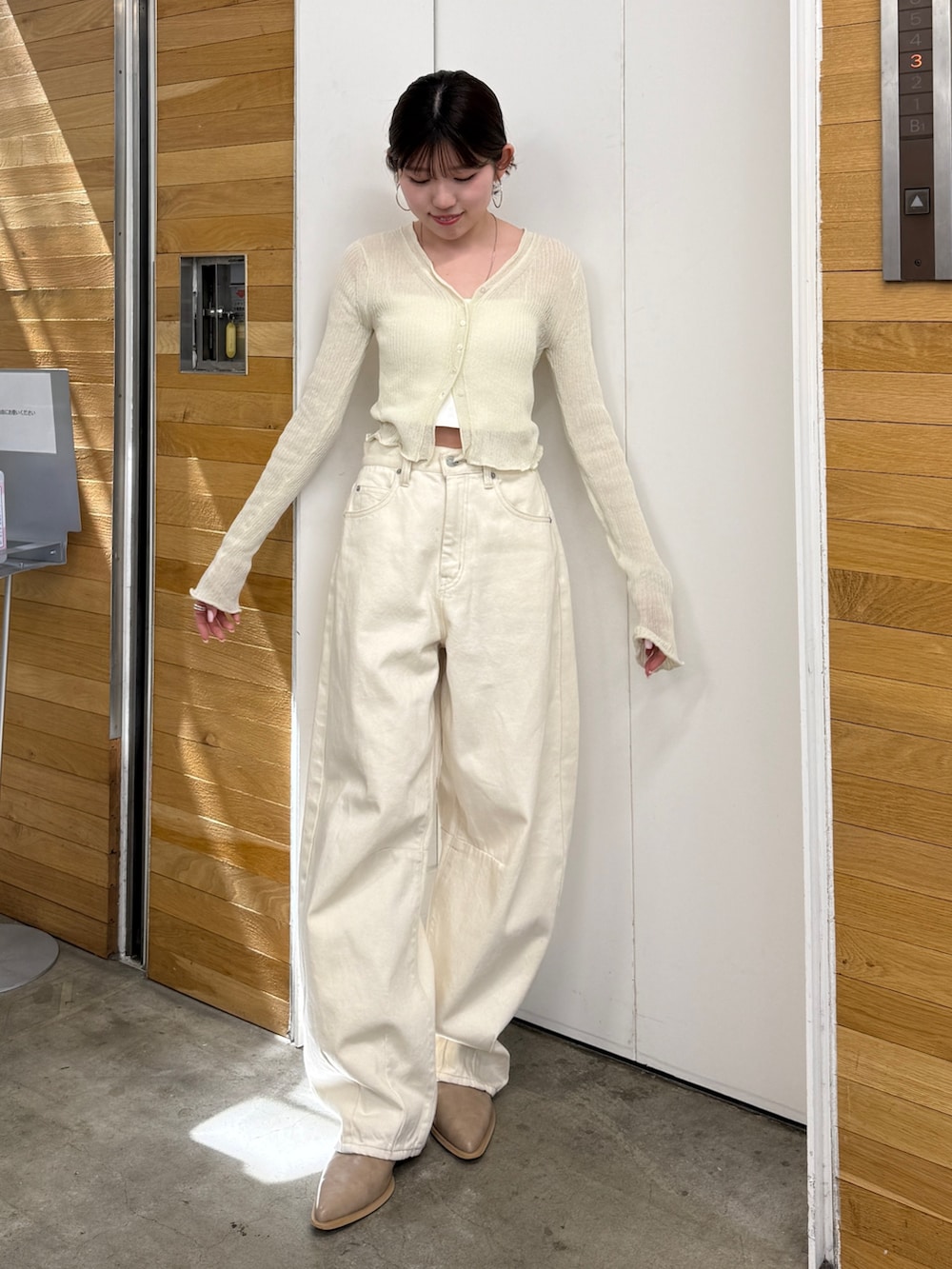 ホワイト系のデニムパンツ、ベージュ系のブーツ、ホワイト系のカーディガン/ボレロを着用したレディースの春コーディネートの3枚目の写真