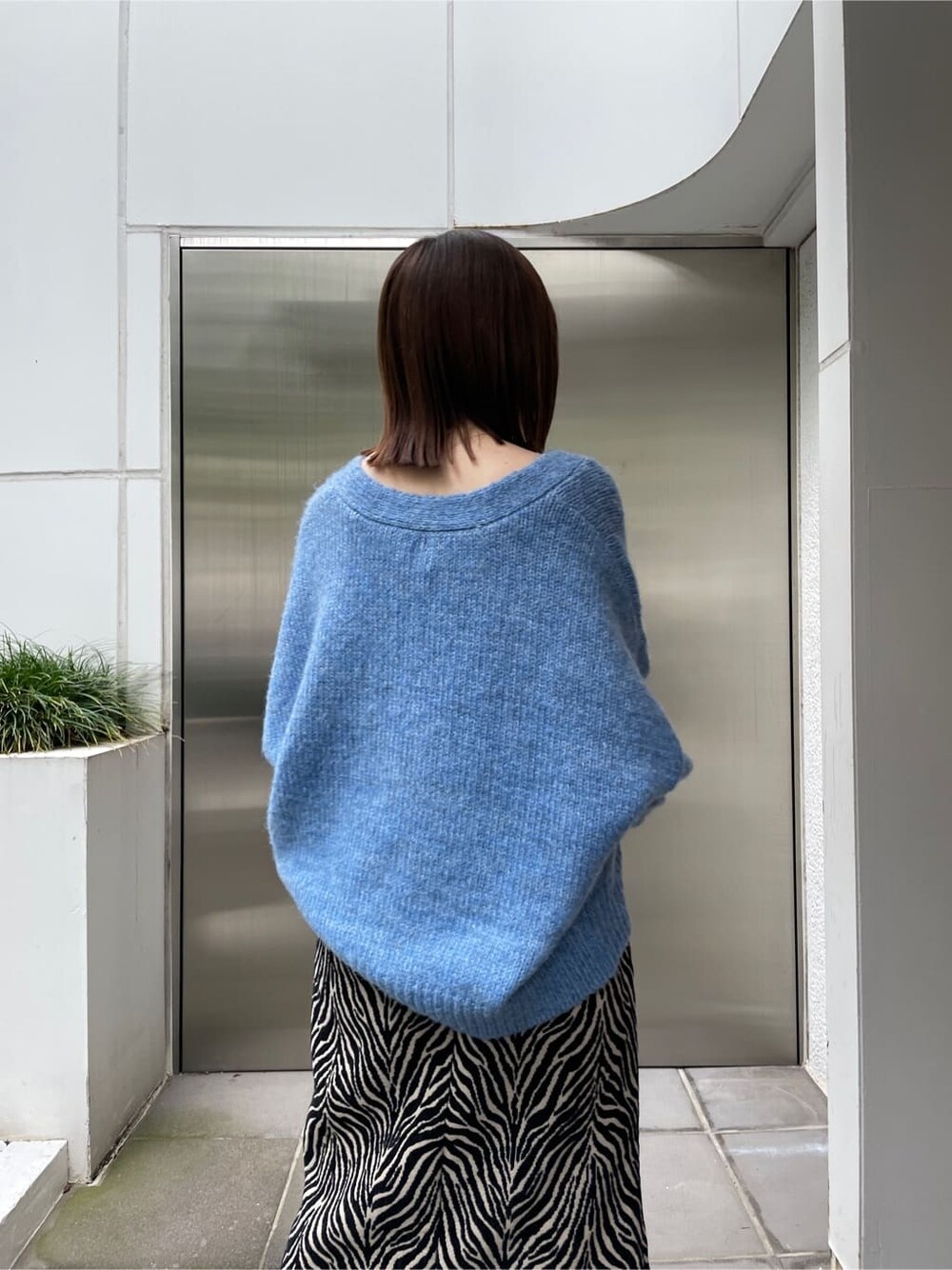 ブラック系のブーツ、ブルー系のカーディガン/ボレロ、ブラック系のスカートを着用したレディースの秋コーディネートの7枚目の写真