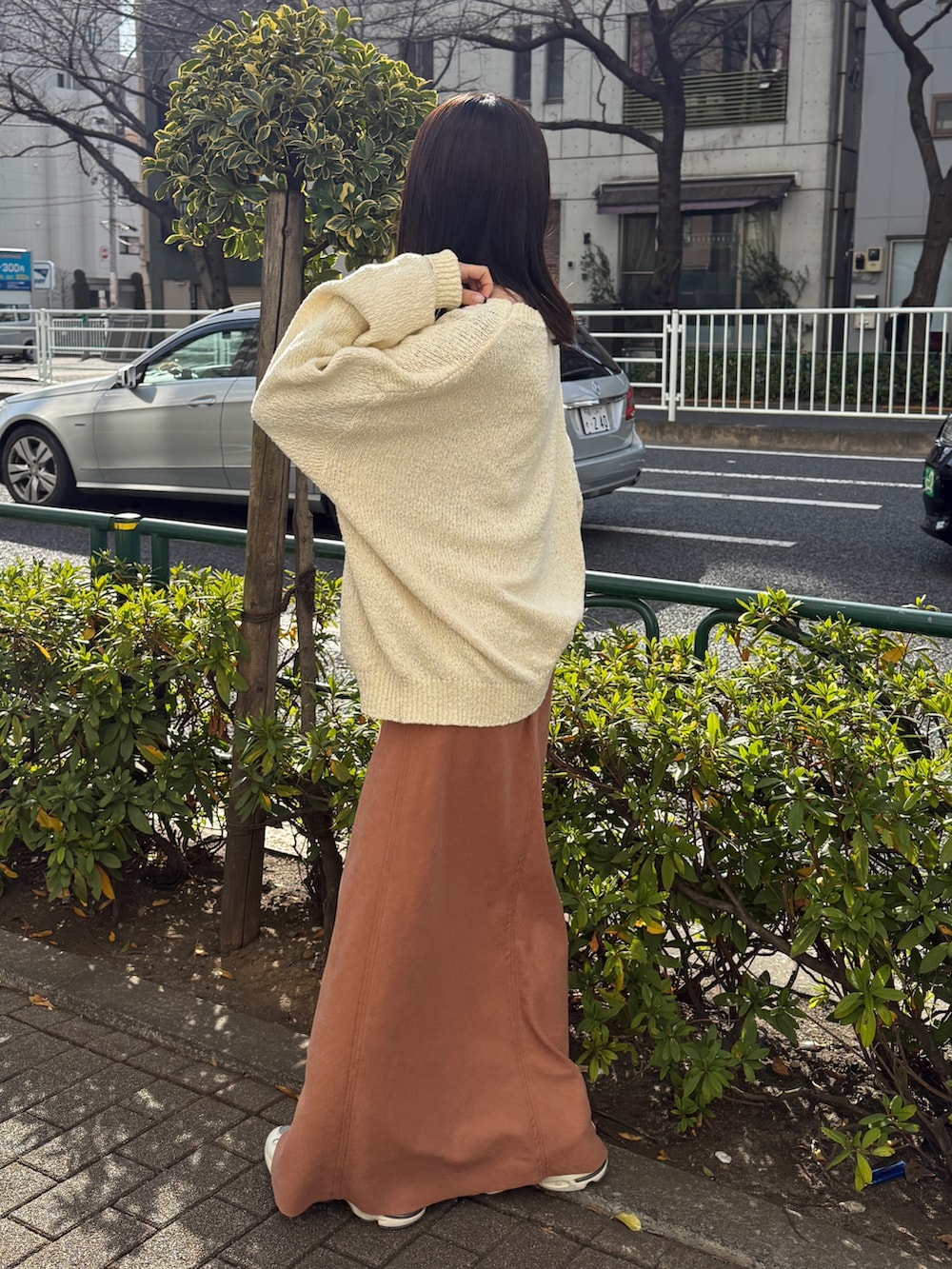 オレンジ系のスカート、ホワイト系のニット/セーターを着用したレディースの冬コーディネートの4枚目の写真