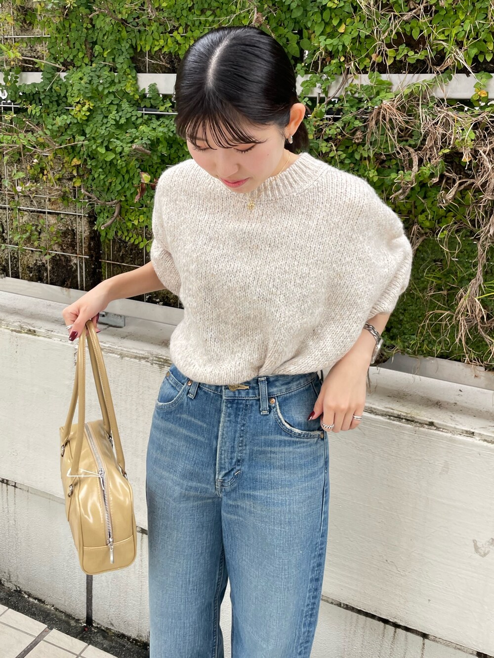 ブルー系のデニムパンツ、ブラウン系のブーツ、ベージュ系のハンドバッグを着用したレディースの秋コーディネートの9枚目の写真