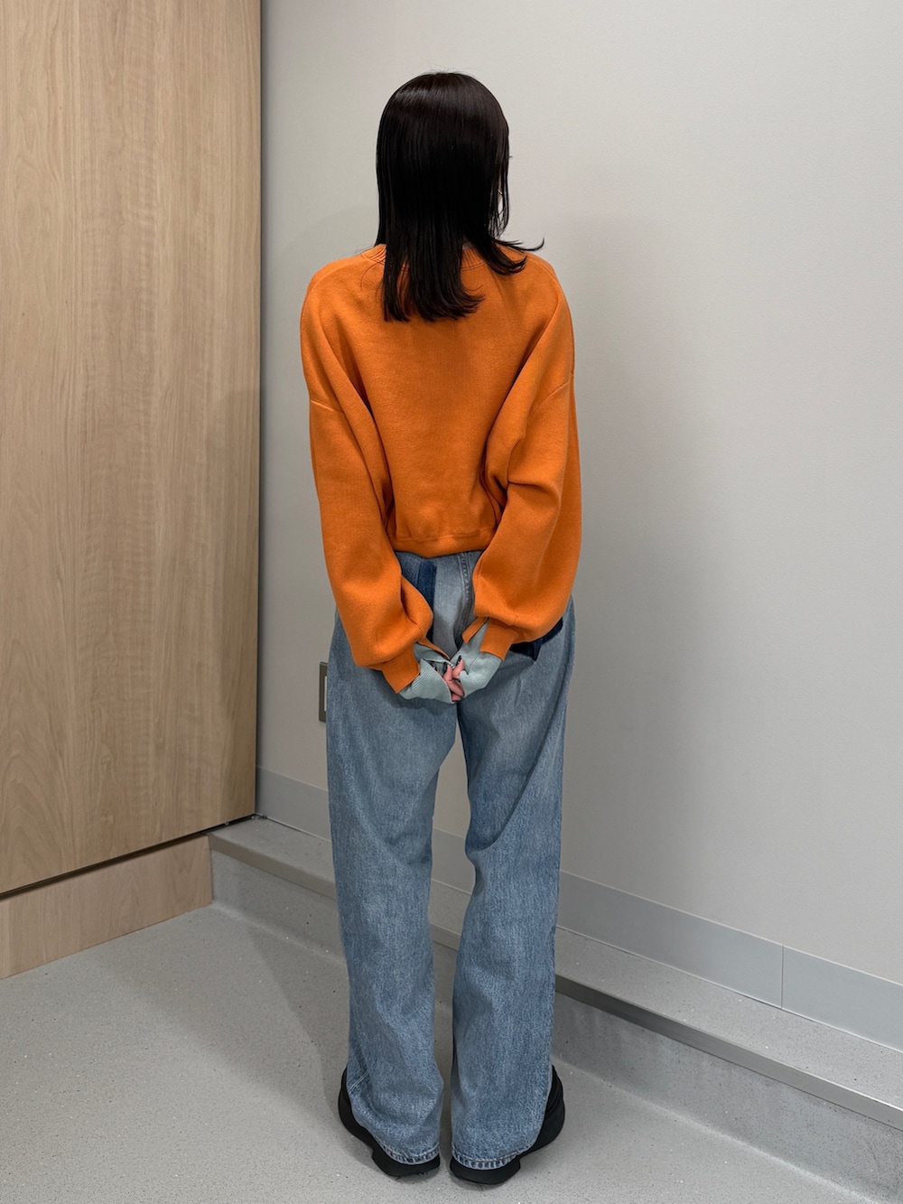 ブルー系のデニムパンツ、オレンジ系のニット/セーター、ブラック系のブーツを着用したレディースの冬コーディネートの3枚目の写真