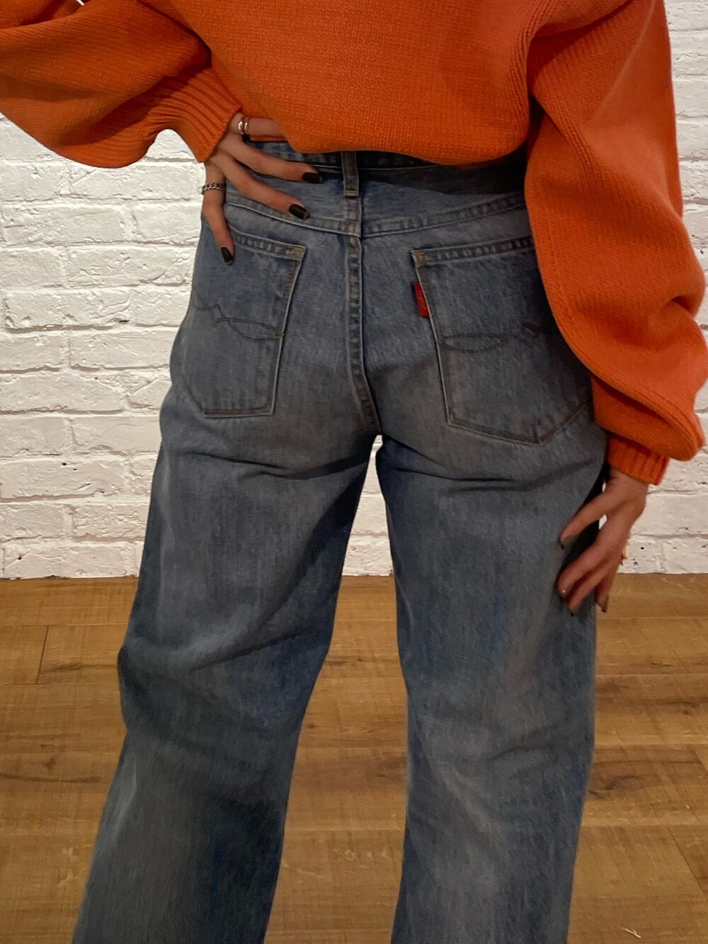 オレンジ系のニット/セーター、ブルー系のデニムパンツ、ブラック系のブーツを着用したレディースの冬コーディネートの6枚目の写真