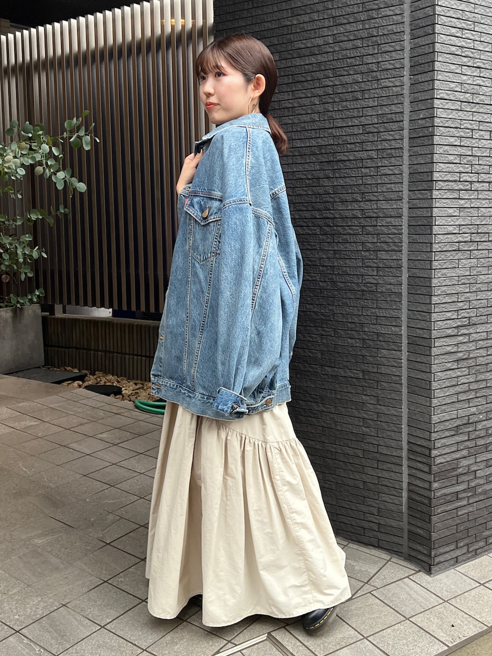 ホワイト系のスカート、ブラック系のブーツ、ブルー系のデニムジャケットを着用したレディースの春コーディネートの9枚目の写真