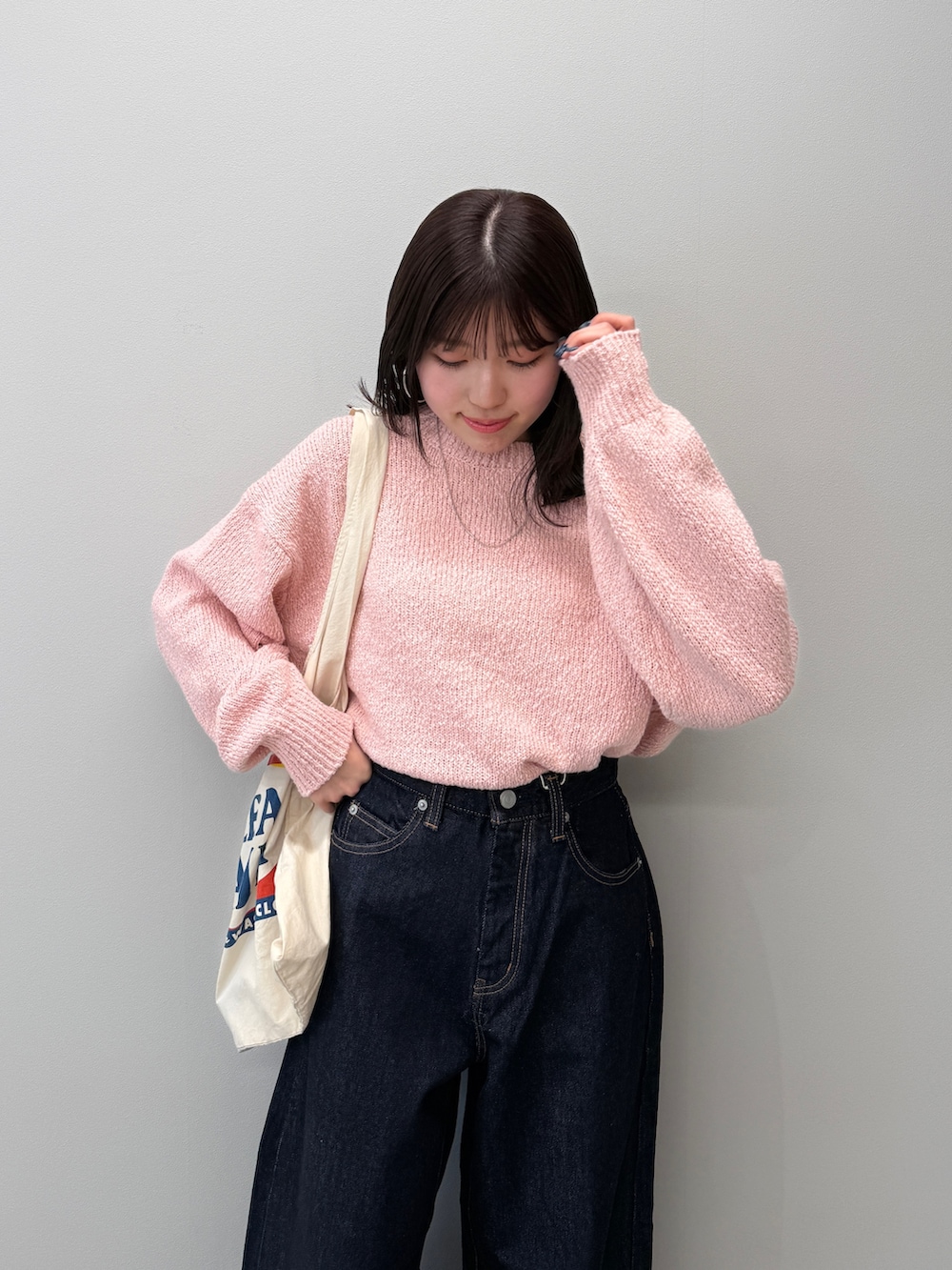 ブルー系のデニムパンツ、ブラック系のブーツ、ピンク系のニット/セーターを着用したレディースの冬コーディネートの5枚目の写真