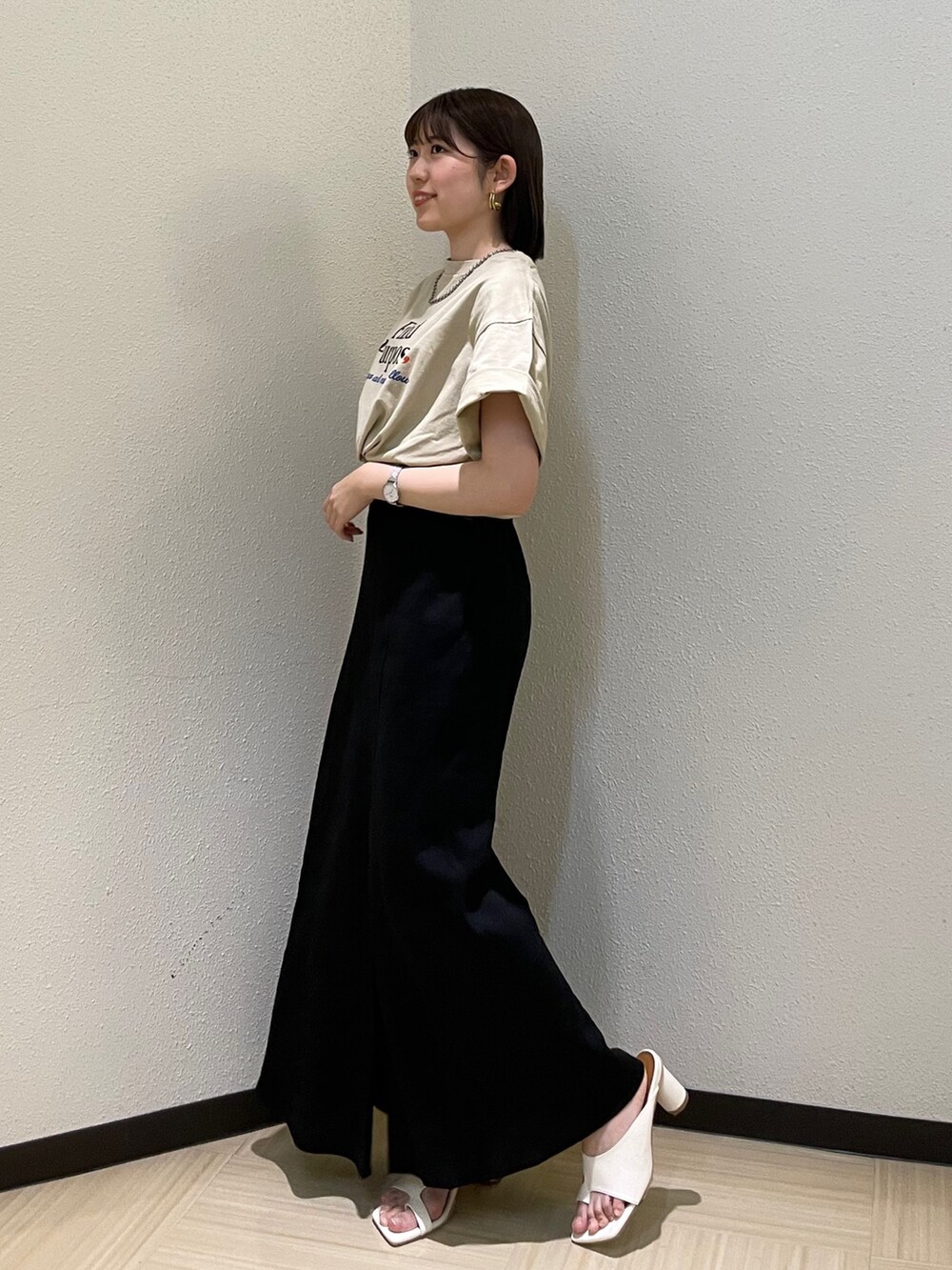 ホワイト系のサンダル、ベージュ系のTシャツ/カットソー、ブラック系のスカートを着用したレディースの春コーディネートの2枚目の写真