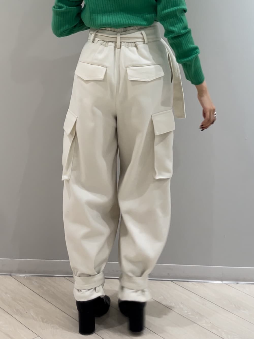 ブラック系のブーツ、ホワイト系のカーゴパンツ、グリーン系のニット/セーターを着用したレディースの冬コーディネートの3枚目の写真