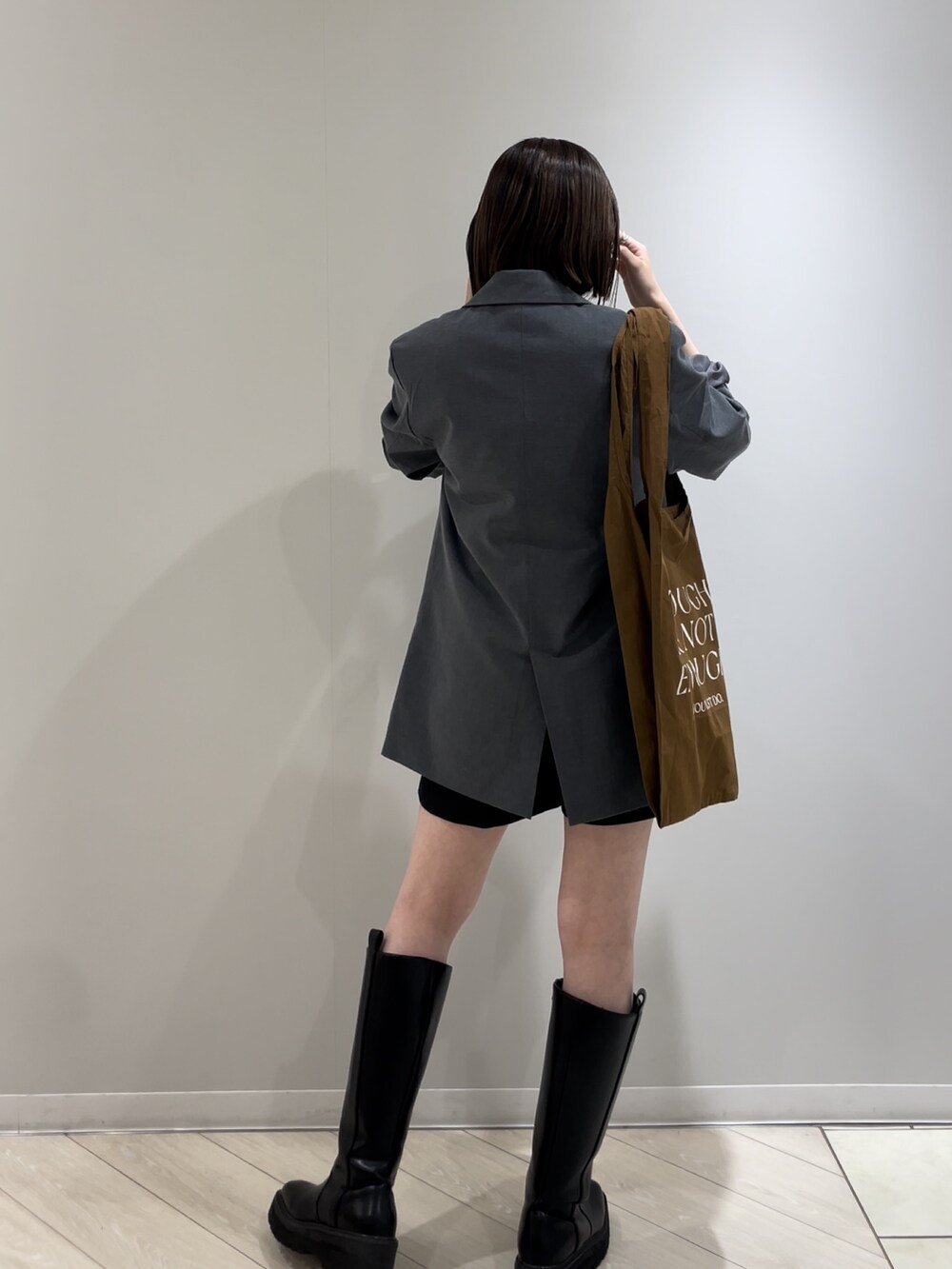 グレー系のテーラードジャケット、グリーン系のタンクトップ、ブラウン系のエコバッグ/サブバッグを着用したレディースの冬コーディネートの6枚目の写真