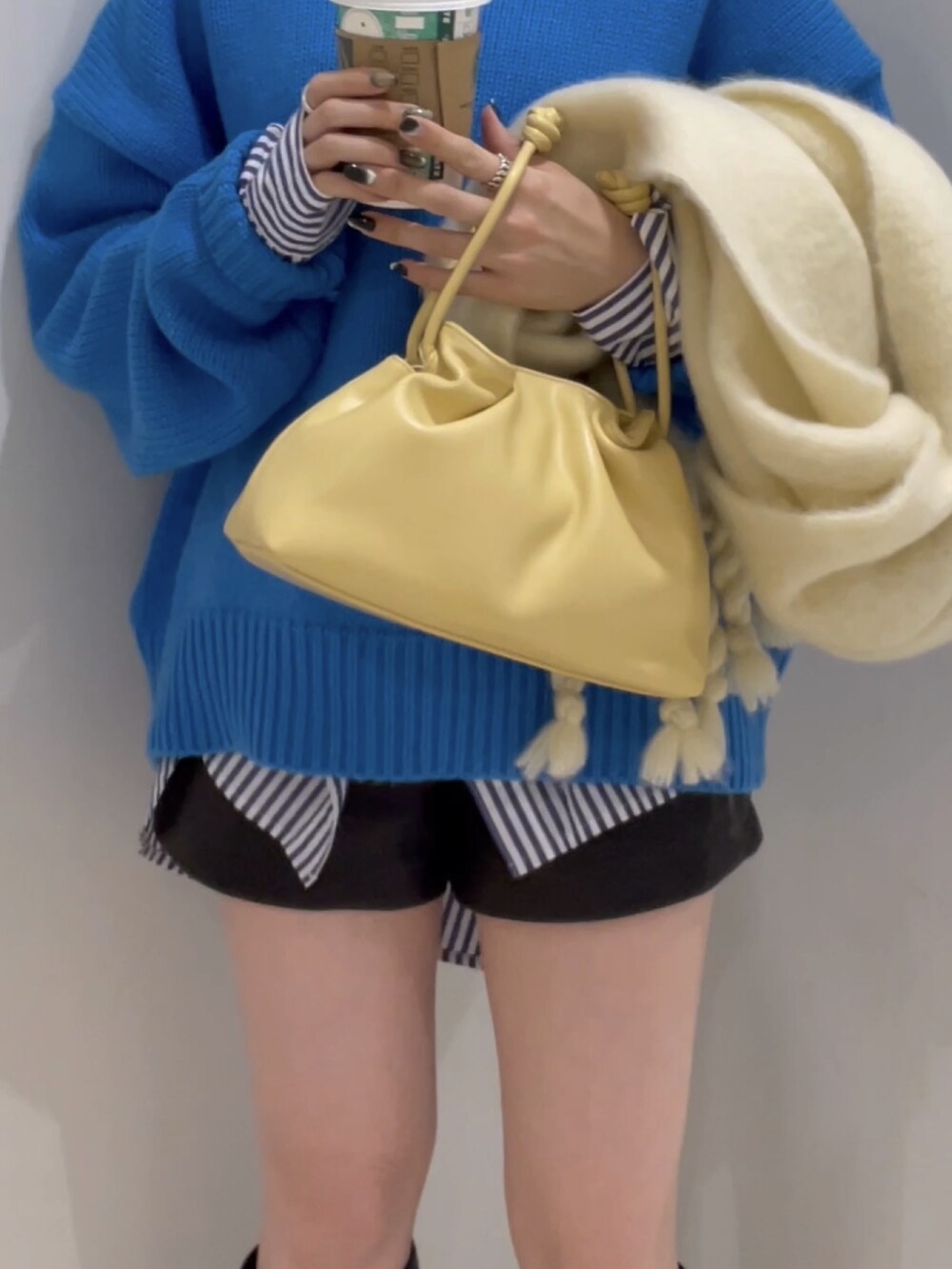 ブルー系のニット/セーター、イエロー系のクラッチバッグ、ブラック系のシューズを着用したレディースの冬コーディネートの5枚目の写真