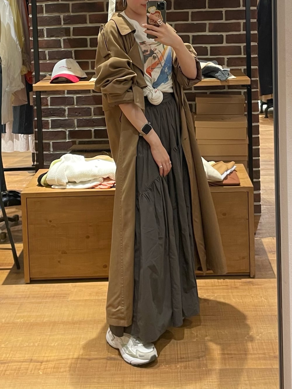 イエロー系のトレンチコート、グレー系のスカート、ホワイト系のTシャツ/カットソーを着用したレディースの春コーディネートの3枚目の写真