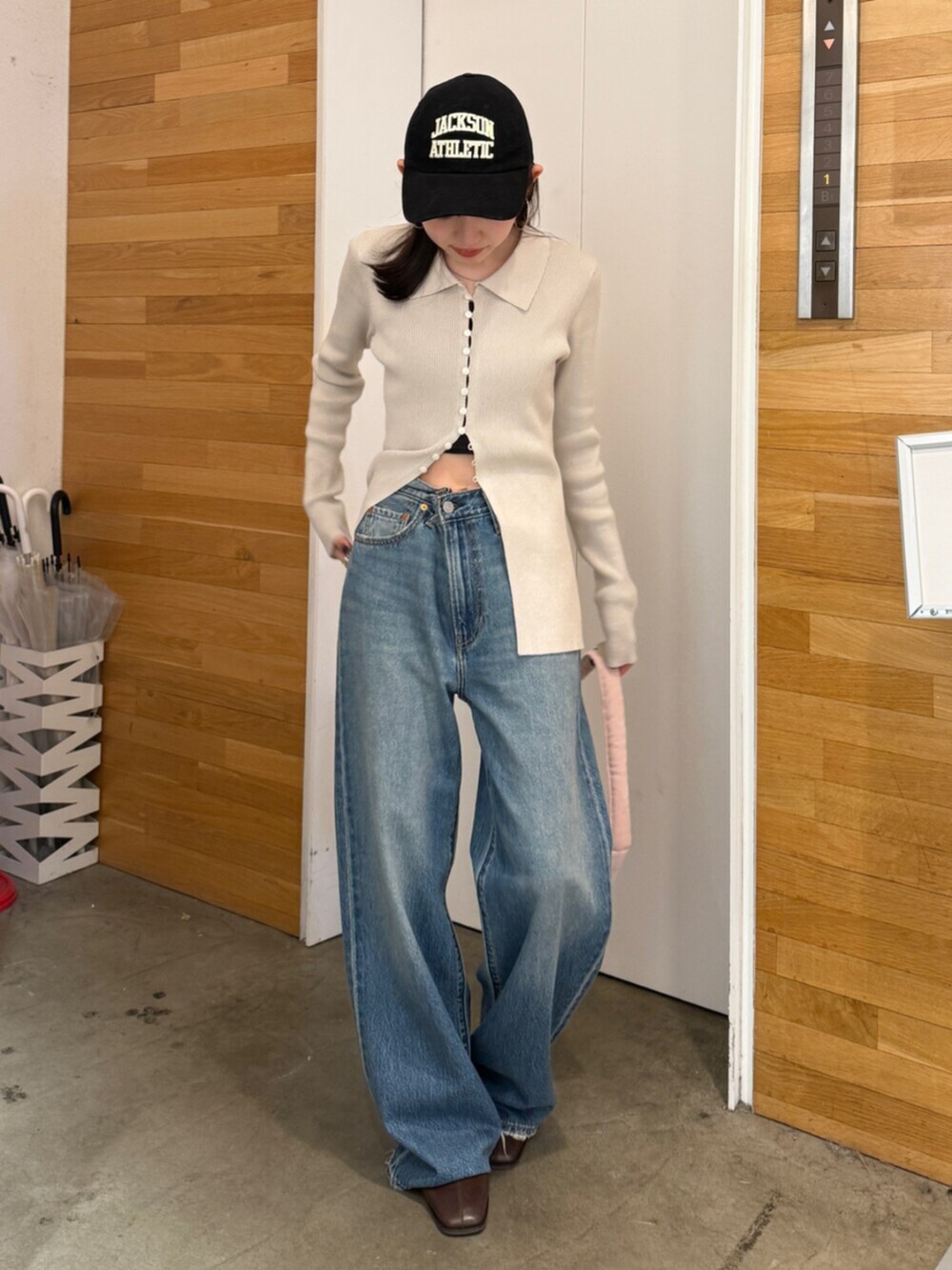 ブラウン系のブーツ、ブルー系のデニムパンツ、ピンク系のハンドバッグを着用したレディースの秋コーディネートの2枚目の写真