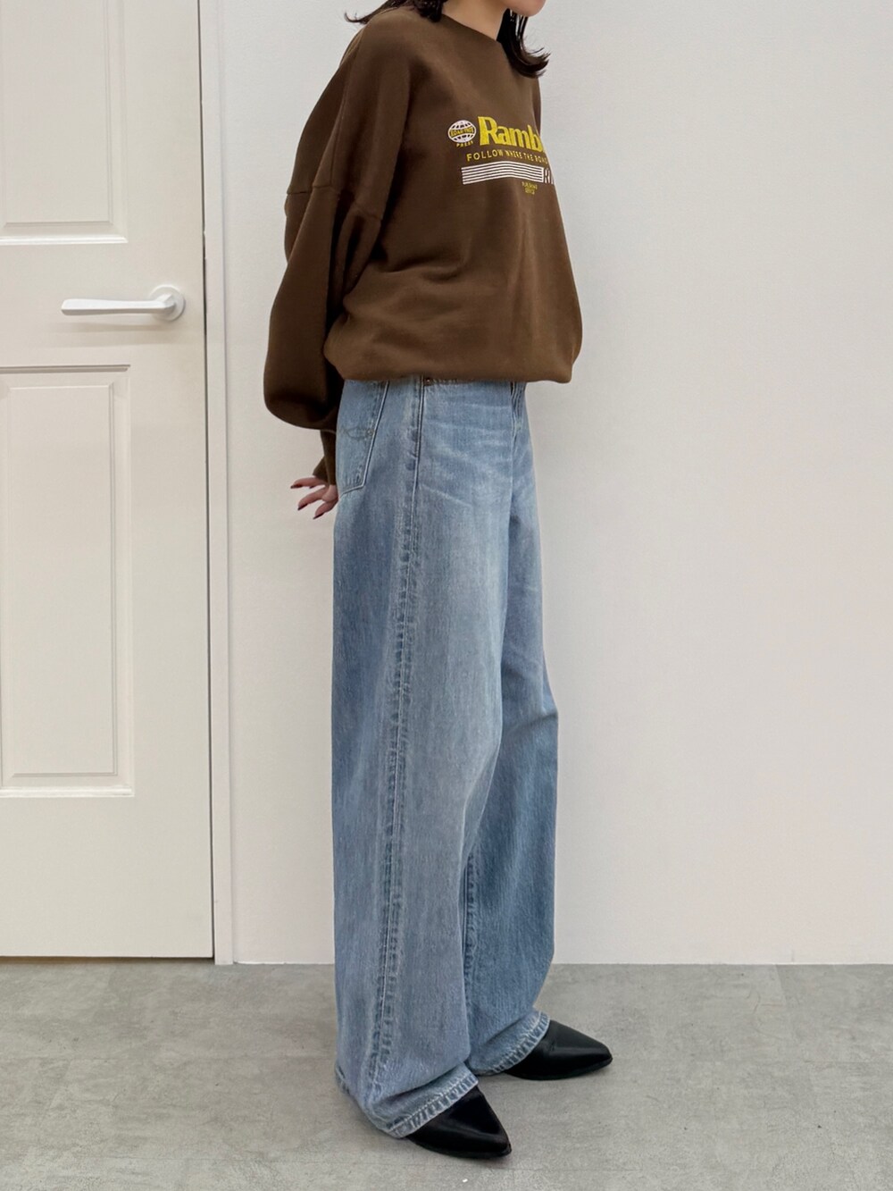 ブルー系のデニムパンツ、ブラック系のブーツ、ブラウン系のスウェットを着用したレディースの秋コーディネートの3枚目の写真