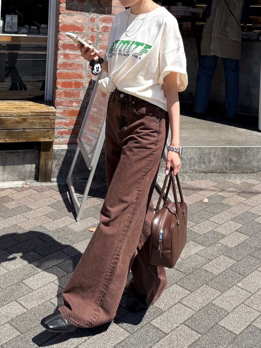 ホワイト系のTシャツ/カットソー、ブラウン系のデニムパンツ、ブラック系のサンダルを着用したレディースの春コーディネートの5枚目の写真