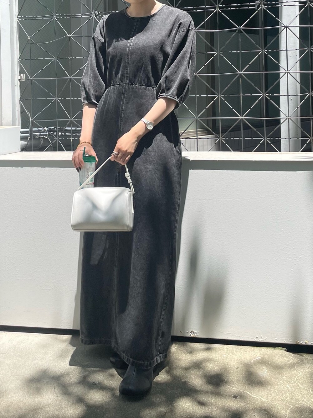 ホワイト系のハンドバッグ、ブラック系のブーツ、ブラック系のワンピースを着用したレディースの夏コーディネートの3枚目の写真