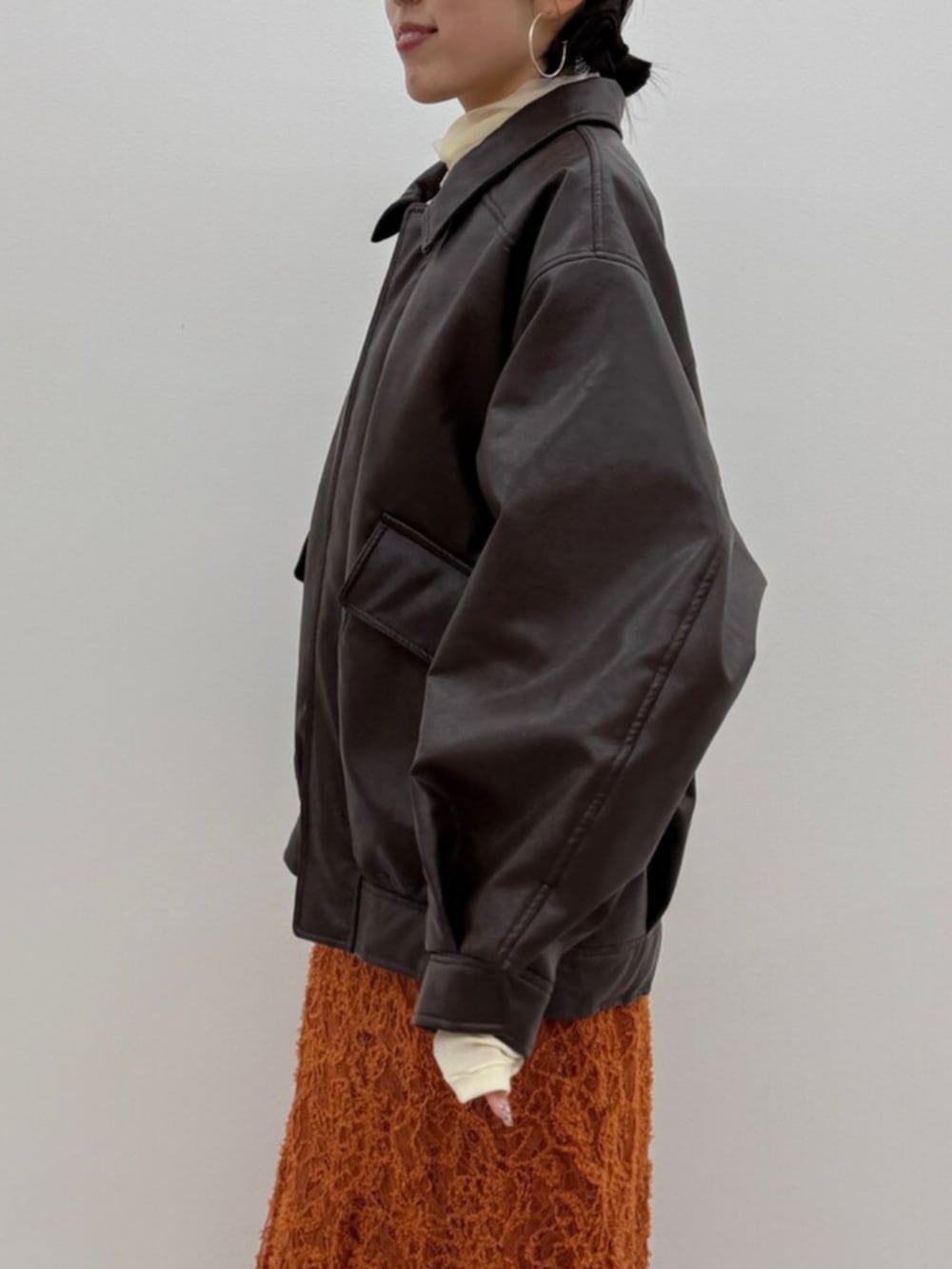 ブラック系のブーツ、ブラウン系のブルゾン、オレンジ系のスカートを着用したレディースの冬コーディネートの5枚目の写真