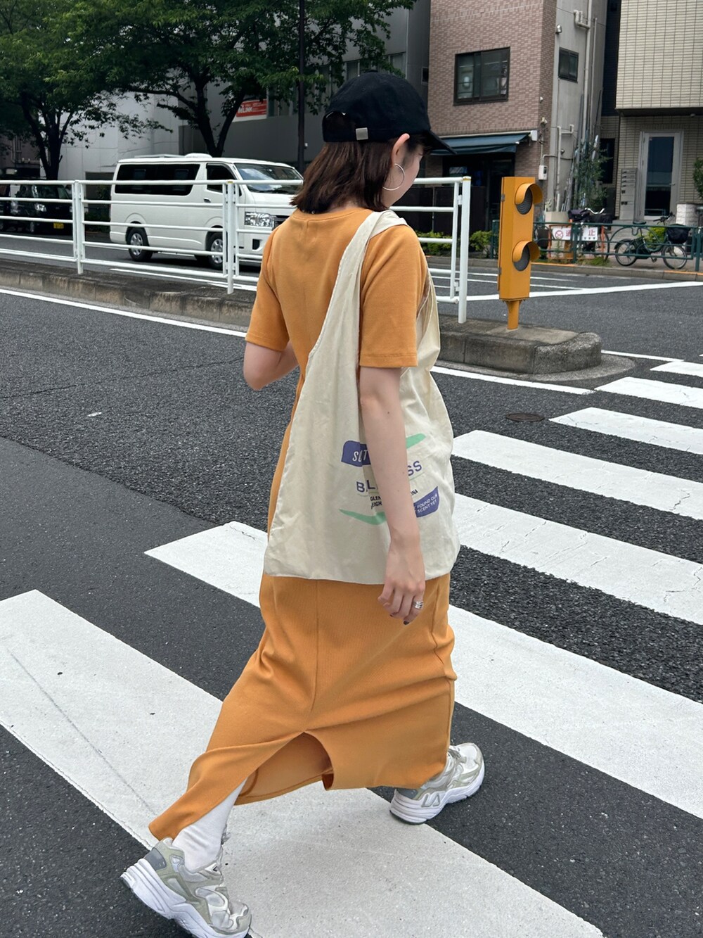 オレンジ系のワンピース、ホワイト系のエコバッグ/サブバッグ、ブラック系のキャップを着用したレディースの夏コーディネートの7枚目の写真