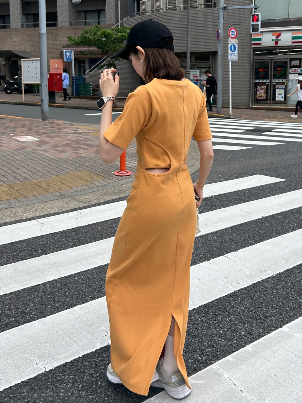 オレンジ系のワンピース、ホワイト系のエコバッグ/サブバッグ、ブラック系のキャップを着用したレディースの夏コーディネートの8枚目の写真
