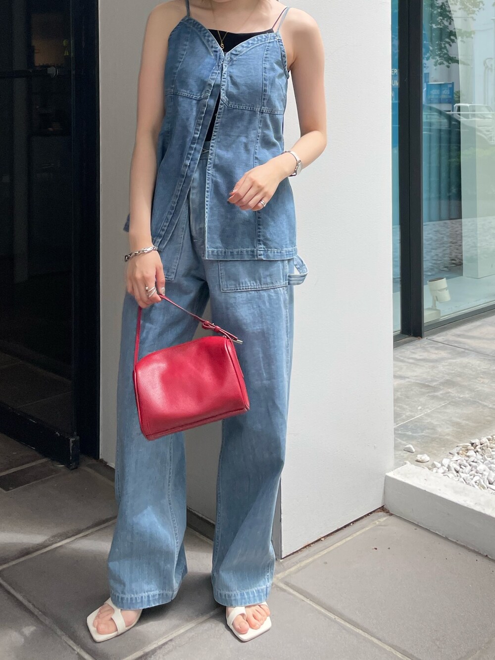 レッド系のハンドバッグ、ホワイト系のサンダル、ブルー系のキャミソールを着用したレディースの春コーディネートの5枚目の写真