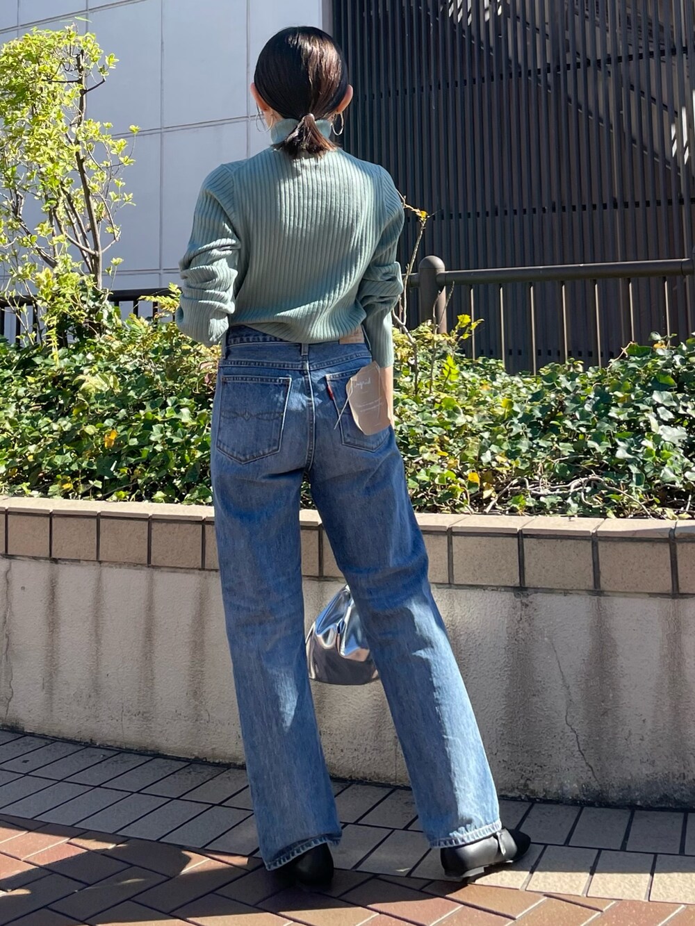 ブラウン系のブルゾン、ブラック系のパンプス、ブルー系のデニムパンツを着用したレディースの秋コーディネートの8枚目の写真