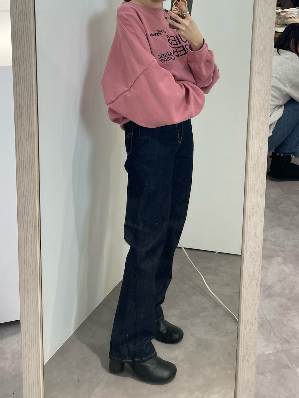 ブラック系のブーツ、ピンク系のスウェット、ブルー系のデニムパンツを着用したレディースの冬コーディネートの3枚目の写真