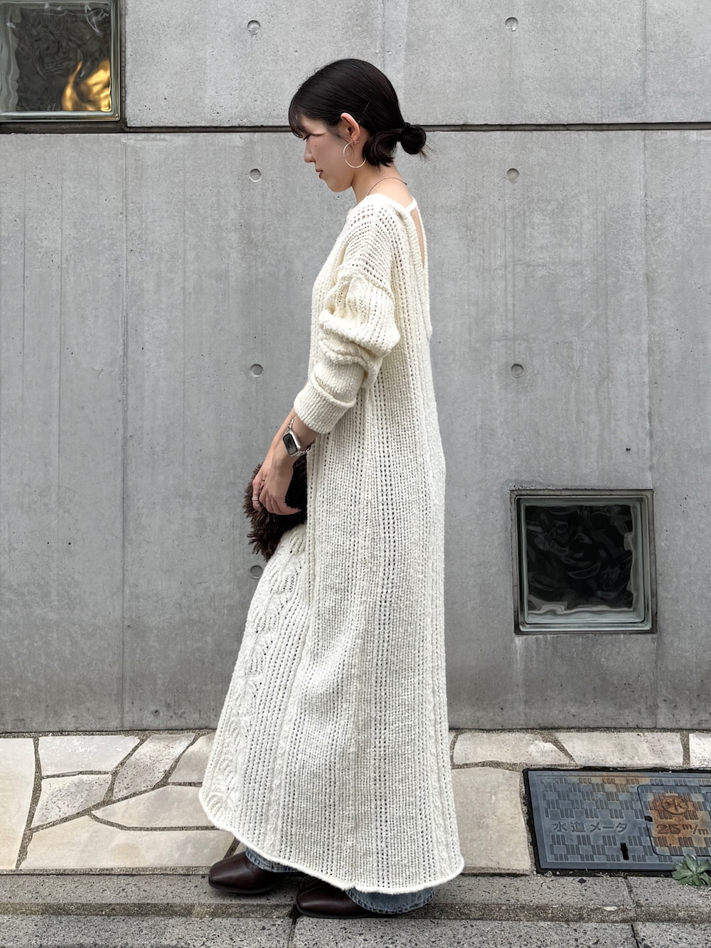 ホワイト系のワンピース、ブルー系のデニムパンツ、ブラウン系のブーツを着用したレディースの冬コーディネートの2枚目の写真