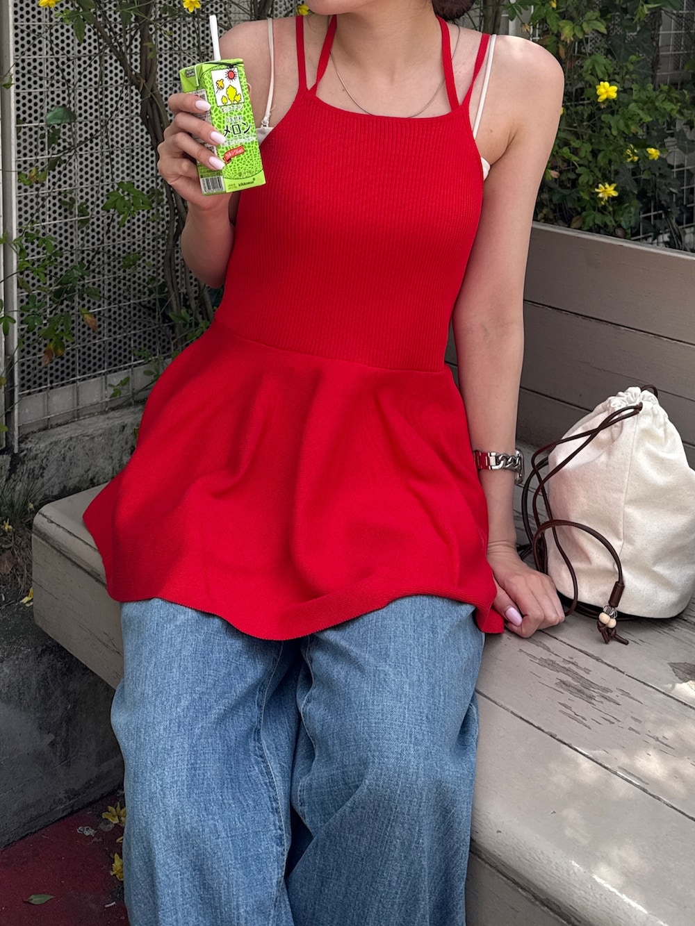 レッド系のキャミソール、ブルー系のデニムパンツ、ブラック系のブーツを着用したレディースの春コーディネートの7枚目の写真