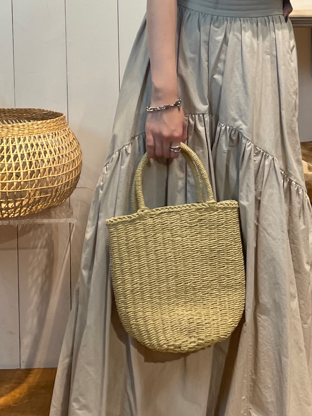 グリーン系のTシャツ/カットソー、ホワイト系のスカート、ベージュ系のかごバッグを着用したレディースの夏コーディネートの8枚目の写真