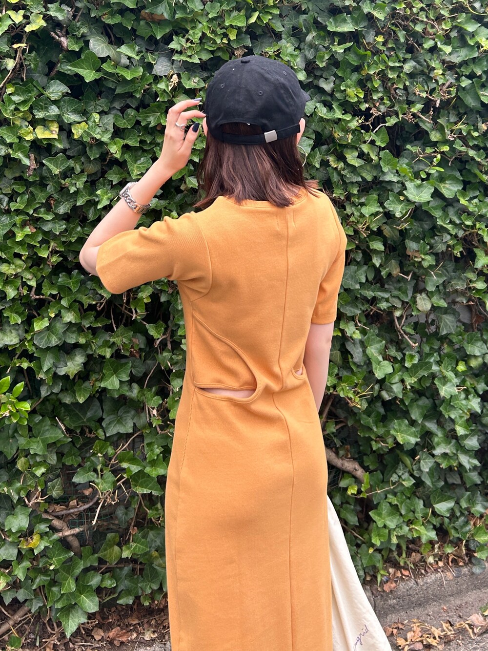 オレンジ系のワンピース、ホワイト系のエコバッグ/サブバッグ、ブラック系のキャップを着用したレディースの夏コーディネートの6枚目の写真
