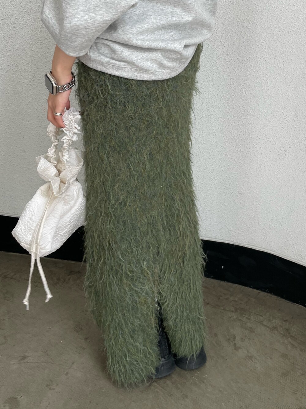 ホワイト系のハンドバッグ、ブラック系のブーツ、グレー系のスウェットを着用したレディースの秋コーディネートの8枚目の写真