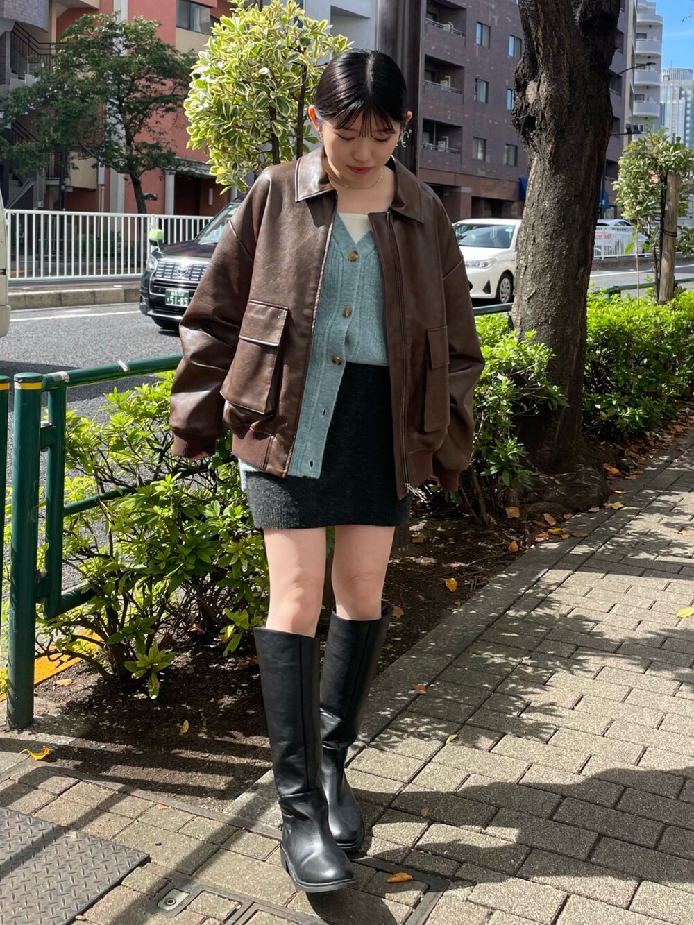 グレー系のスカート、ブラック系のブーツ、ブラウン系のブルゾンを着用したレディースの秋コーディネートの2枚目の写真