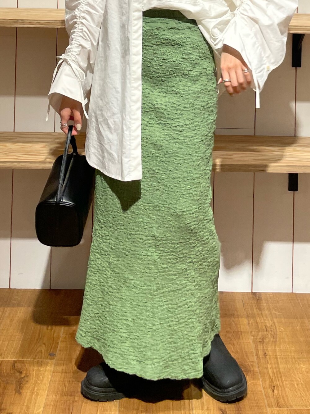 ブラック系のハンドバッグ、ブラック系のブーツ、ホワイト系のシャツ/ブラウスを着用したレディースの冬コーディネートの5枚目の写真