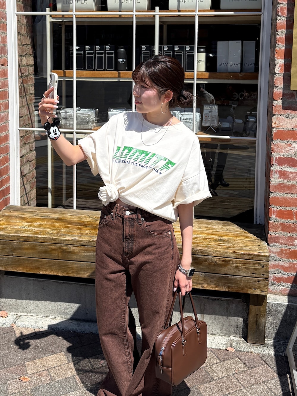 ホワイト系のTシャツ/カットソー、ブラウン系のデニムパンツ、ブラック系のサンダルを着用したレディースの春コーディネートの4枚目の写真