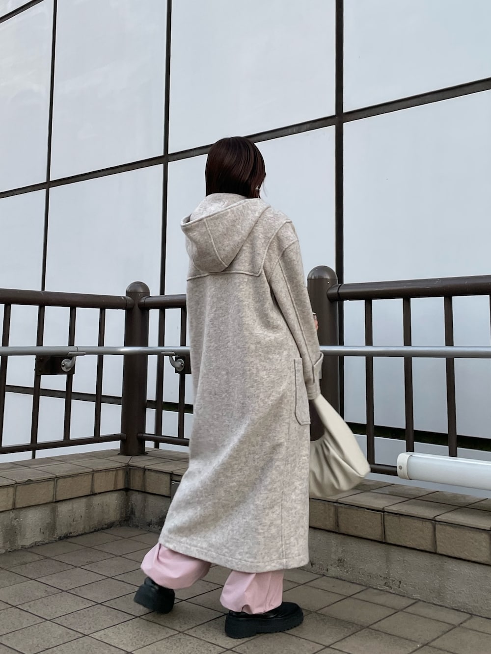 ピンク系のカーゴパンツ、ホワイト系のハンドバッグ、ホワイト系のダッフルコートを着用したレディースの冬コーディネートの3枚目の写真